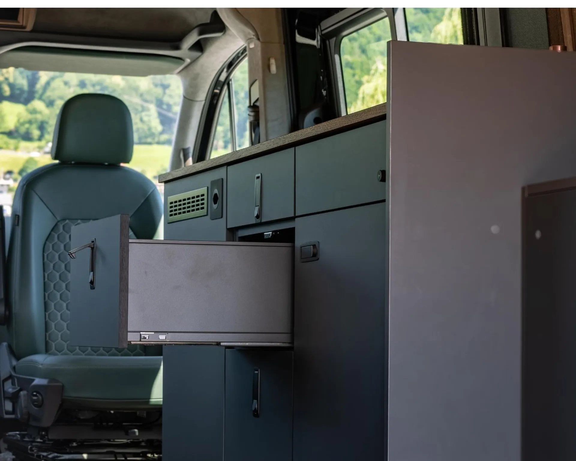 Möbelbau in einem Camper Van. Antrazitfarbenes Möbel mit mehreren Schubladen uns Schränken