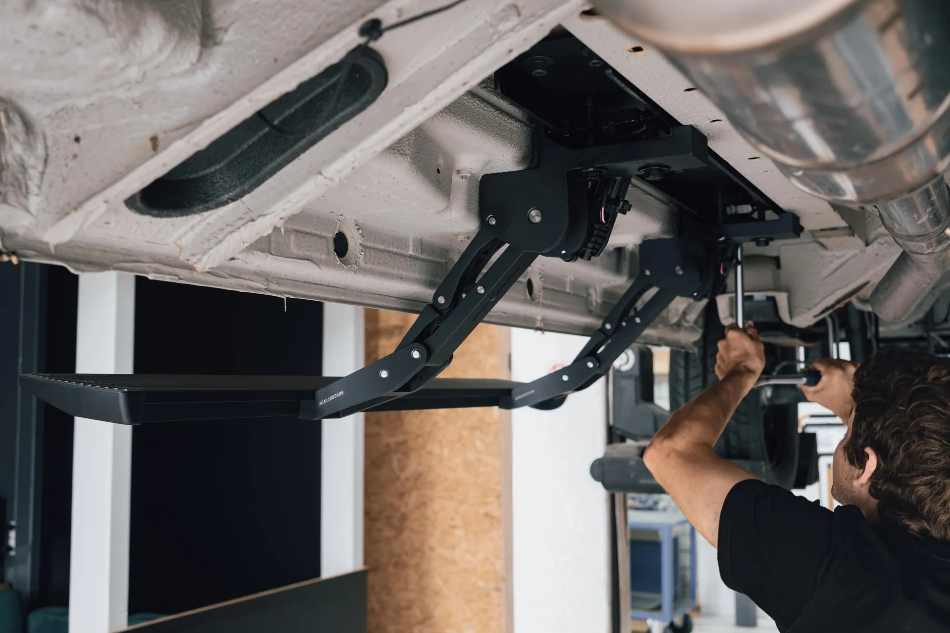 Handwerker von Cocoon Vans der eine Trittstufe an einem Fahrzeug montiert