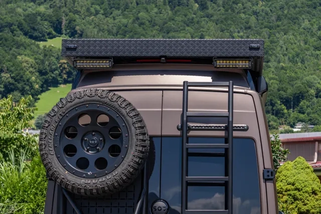 Ansicht von hinten mit geschlossenen Hecktüren. zu sehen sind zusätzlich angebrachte heckbeleuchtung, ein Ersatzrad und eine Leiter um auf das Dach zu gelangen